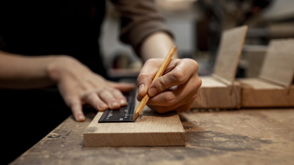 a woman measures wood before cutting it, actively engaged on a construction job site